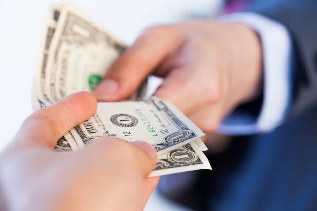 A man gives money to another person