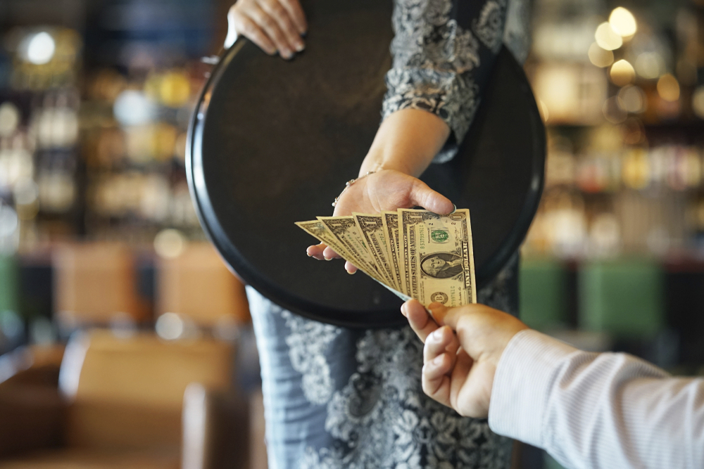 A waitress takes cash for a tip