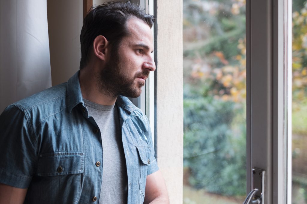 A man looks outside of his window