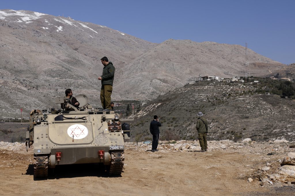 Israeli soldiers stand atop an armored carrier